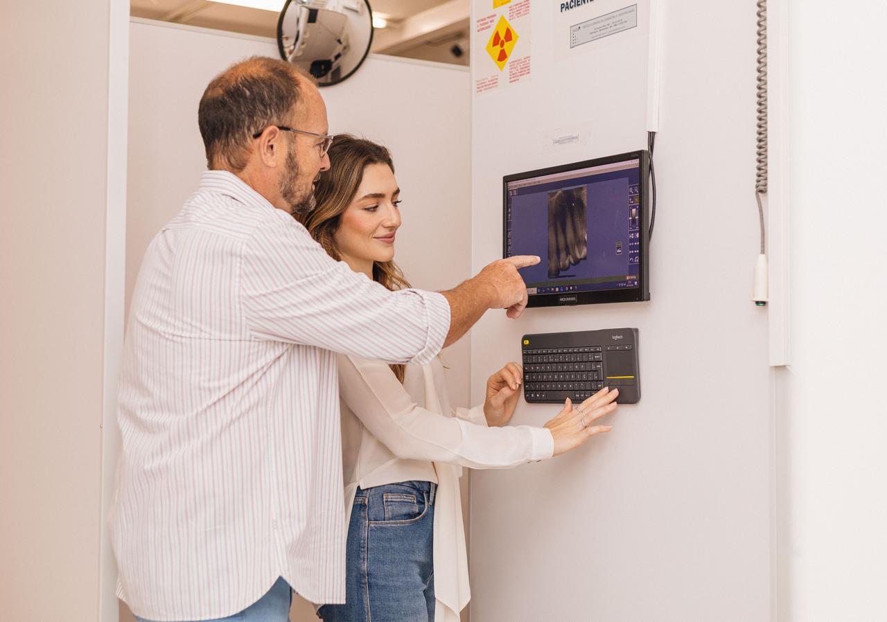 Profissional da RX Digital mostrando exame radiográfico digital a uma paciente